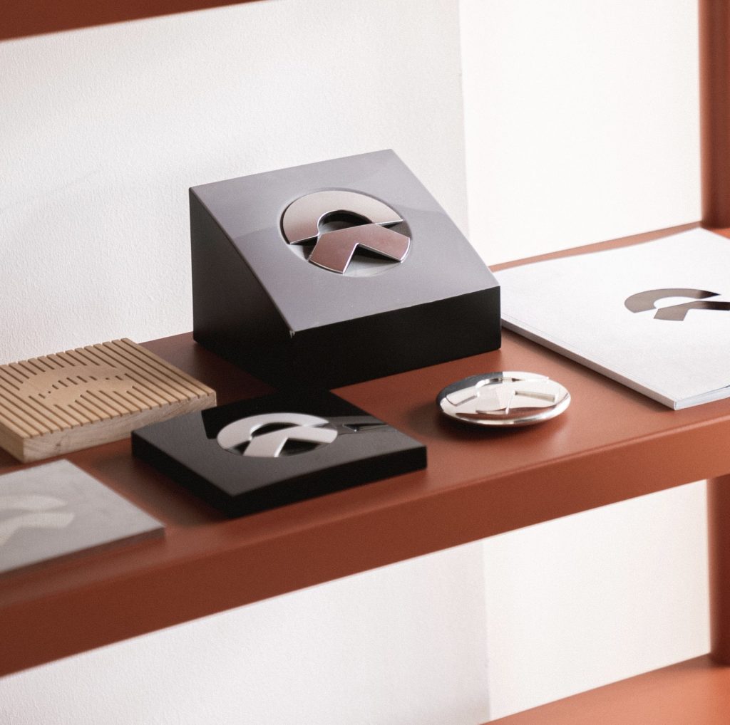 Photograph of NIO brand symbol badges showcasing different material. Film, design and produce by forpeople.